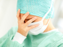 Closeup portrait of a disappointed young lady surgeon with her hand on her face