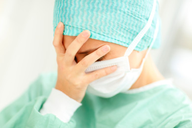 Closeup portrait of a disappointed young lady surgeon with her hand on her face